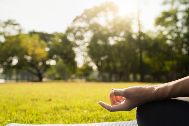 Jovem mulher asiática ioga ao ar livre manter a calma e medita enquanto pratica ioga para explorar a paz interior. Yoga tem bons benefícios para a saúde perto do lago no parque. Esporte e conceito de estilo de vida saudável
. - Foto, Imagem