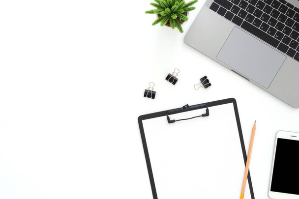 Creative flat lay photo of workspace desk. Top view office desk with laptop, phone, pencil, blank clipboard and plant on white color background. Top view with copy space, flat lay photography. - Foto, Bild
