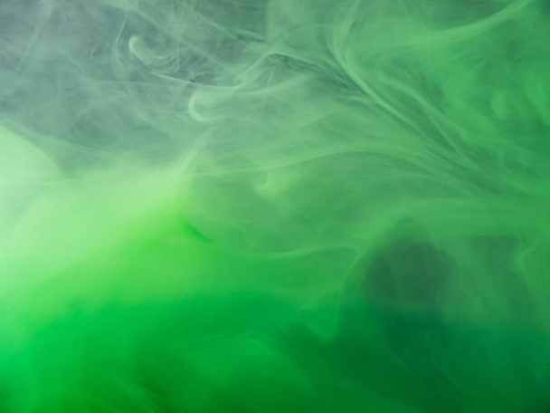 Green acrylic paint dissolving into water, abstract pattern. Close up view. Blurred background. Acrylic smoke under water, abstract background. Paint in liquid. Abstract art for wallpapers. - Photo, Image