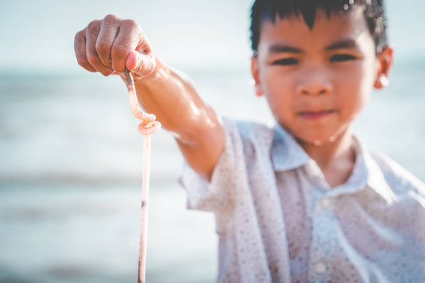 Дети держат пластиковую соломинку, которую он нашел на пляже.
 - Фото, изображение