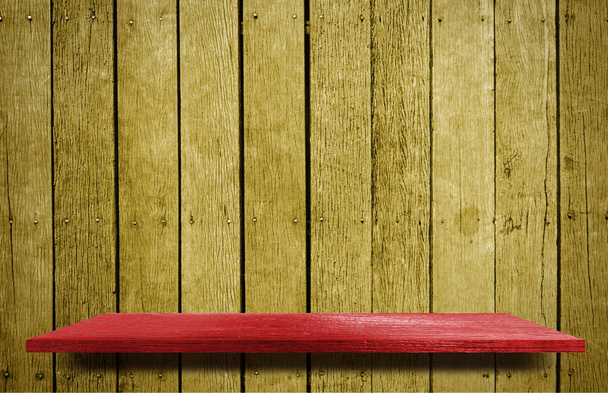 Červená police na pozadí textury na žluté dřevěné zdi.  - Fotografie, Obrázek