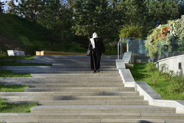 A Muslim woman climbs up the stairs to the terrace of a street cafe. - Фото, зображення