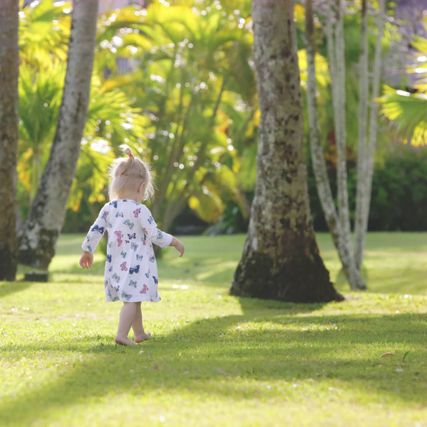  Adorable baby girl in the beautiful tropical park, candid outdoor portrait - Foto, Imagen