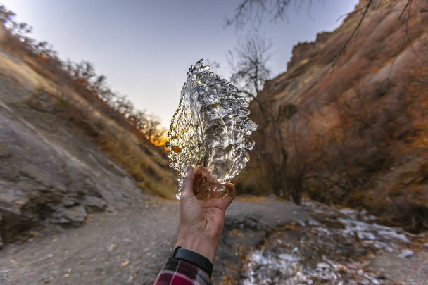 Человек держит полупрозрачный и блестящий кусок льда против
  - Фото, изображение