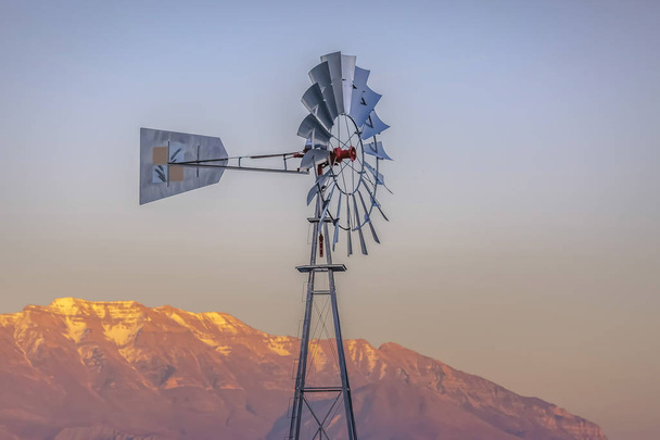 Windpump with a rugged golden mountain and cloudy sky background - Foto, imagen