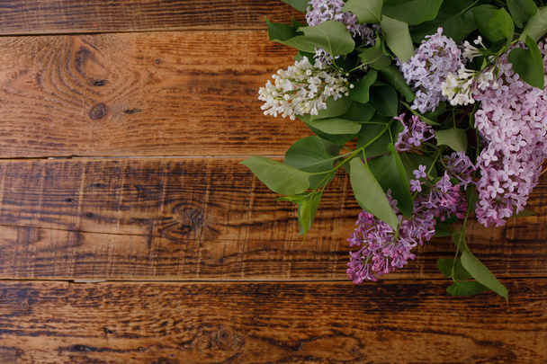 Decor of flowers on the background of vintage wooden planks.Vintage background with lilac flowers and place under the text. View from above. Flat lay. - Foto, afbeelding