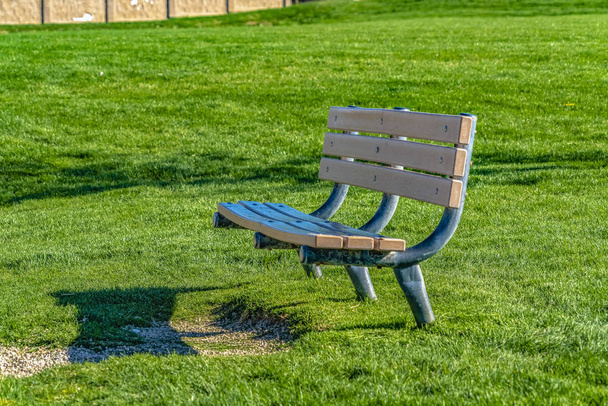 Close up of an empty bench against a rich green grassy field on  - Photo, Image