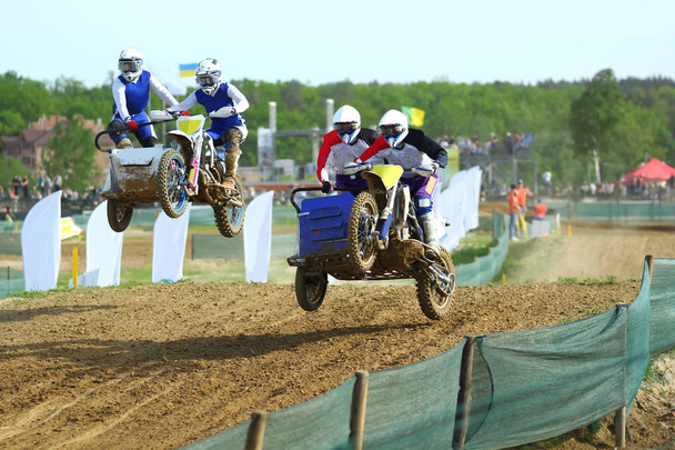 Atletas de motocross Sidecar adelantándose en el salto de aire en la pista de tierra
  - Foto, imagen