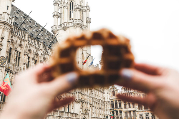 View of Brussels Town Hall at the Grand Place in Brussels through a hole in the traditional Belgian waffle. - 写真・画像