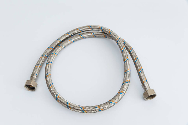 Flexible water pipe in metal braid on white background twisted into a ring - Valokuva, kuva