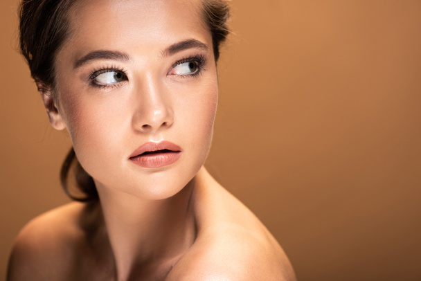 young beautiful naked woman with shiny makeup looking away isolated on beige with copy space - Fotografie, Obrázek