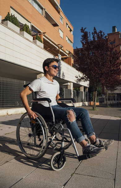 Portrait of cute boy sitting on wheelchair outdoor - Foto, Imagem