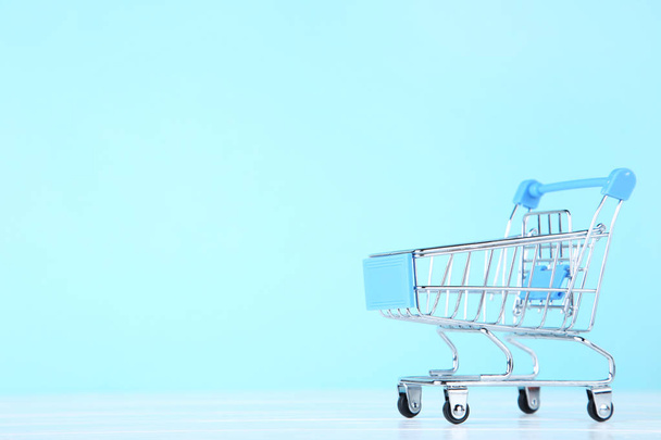 Small shopping cart on blue background - Foto, imagen