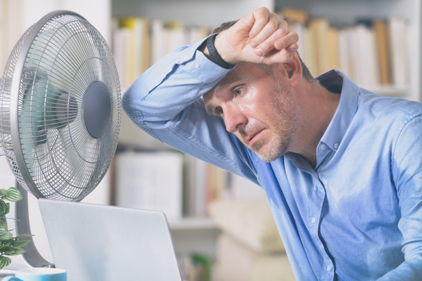 Człowiek cierpi z powodu ciepła w biurze lub w domu - Zdjęcie, obraz