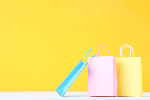 Small paper shopping bags on yellow background - Foto, Imagen