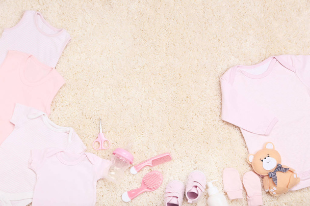 Clothes with toy and baby supplies on carpet - Фото, изображение