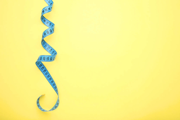 Blue measuring tape on yellow background - 写真・画像