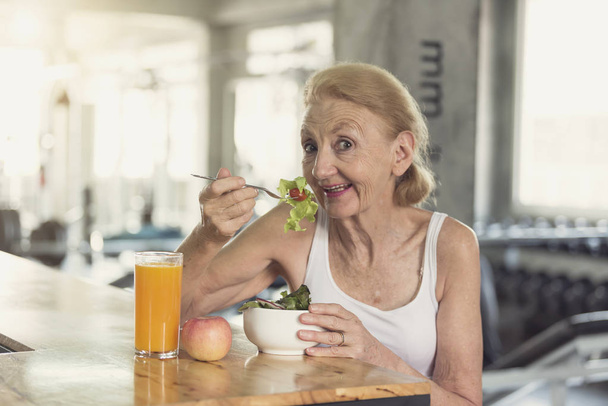 年配の女性のヘルシー サラダ、オレンジ ジュースを食べる.  - 写真・画像