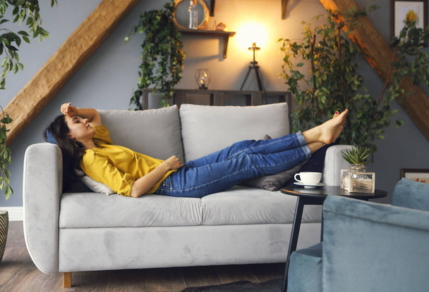 Młoda brunetka relaksująca się na kanapie po długim dniu - Zdjęcie, obraz
