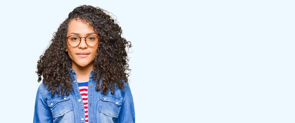 Young beautiful woman with curly hair wearing glasses Relaxed with serious expression on face. Simple and natural looking at the camera. - Photo, Image