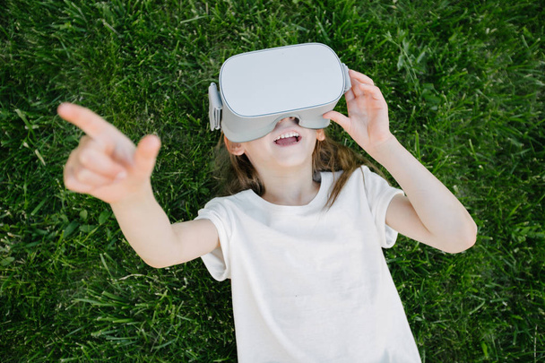 Kid girl using virtual reality glasses outside - Фото, изображение