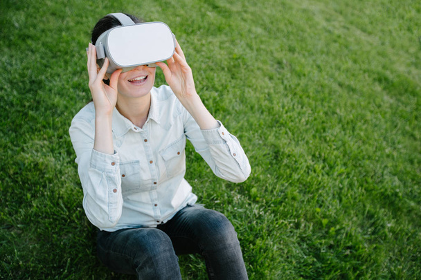 Woman using virtual reality glasses outside on a green grass - 写真・画像