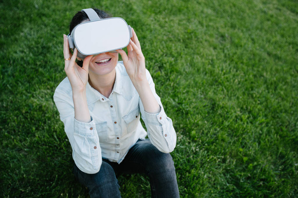 Woman using virtual reality glasses outside on a green grass - 写真・画像