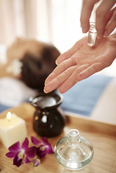 Hands of cosmetologist using essential oils for rejuvenating face massage  - Photo, Image