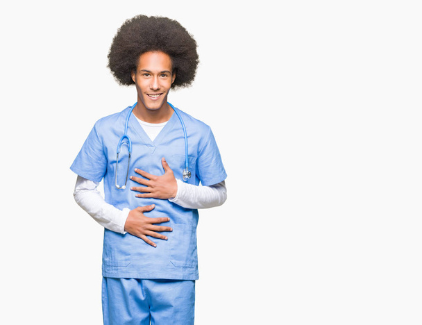 Young african american doctor man with afro hair with hand on stomach because nausea, painful disease feeling unwell. Ache concept. - Photo, Image