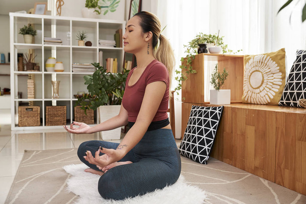 hübsche junge asiatische Frau praktiziert Meditation zu Hause - Foto, Bild