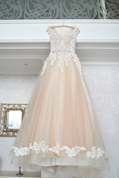 Beautiful beige embroidered wedding dress hanging on hanger agai - Foto, immagini
