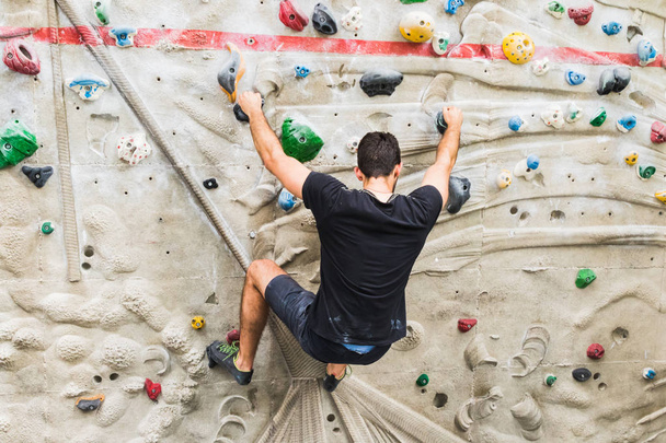 Man beoefenen klimmen op kunstmatige muur binnenshuis. Actieve  - Foto, afbeelding