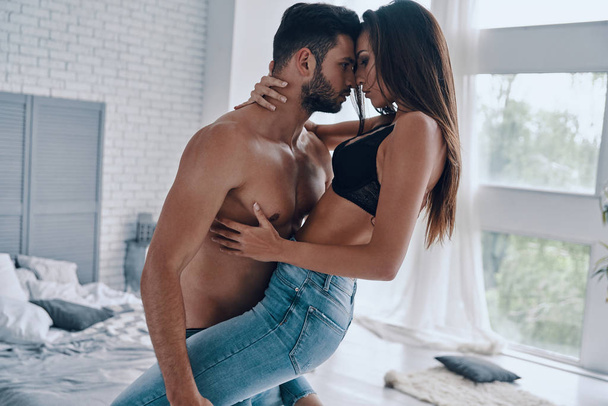 Beautiful young couple embracing, man holding and carrying woman, passion  - Φωτογραφία, εικόνα