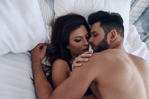 Top view of beautiful young couple making love while lying in the bed - Photo, image
