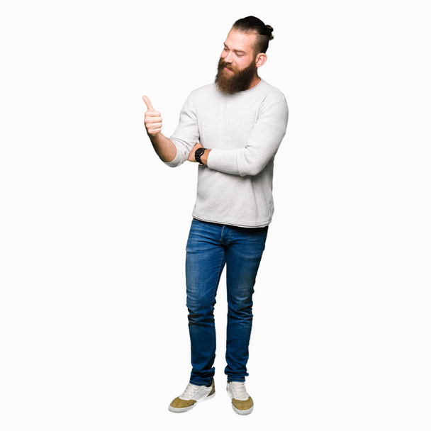Fiatal szőke férfi viselő alkalmi pulóvert keres büszke, mosolyogva csinál remek gesztus az oldalára - Fotó, kép