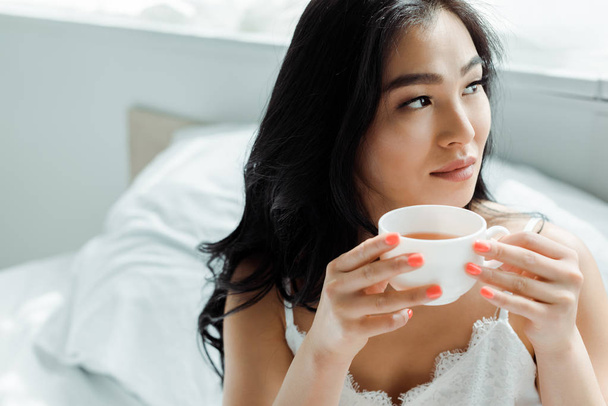 selective focus of pretty thai woman holding cup with tea  - Foto, imagen