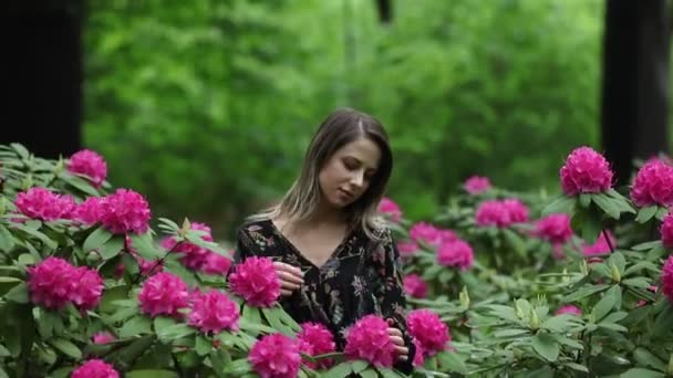 style woman near rhododendron flowers in a garden in spring time - Felvétel, videó