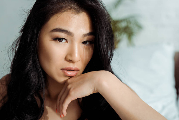 sensual asian young woman touching face and looking at camera - Фото, изображение