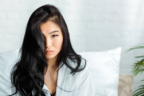 attractive brunette thai woman looking at camera in bedroom  - Fotografie, Obrázek