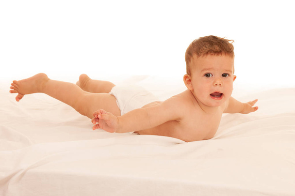 Hapy bebê menino em jogar na cama isolado sobre branco
  - Foto, Imagem