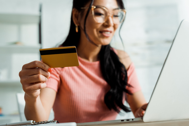 selective focus of asian woman in glasses holding credit card and using laptop  - Foto, Imagem