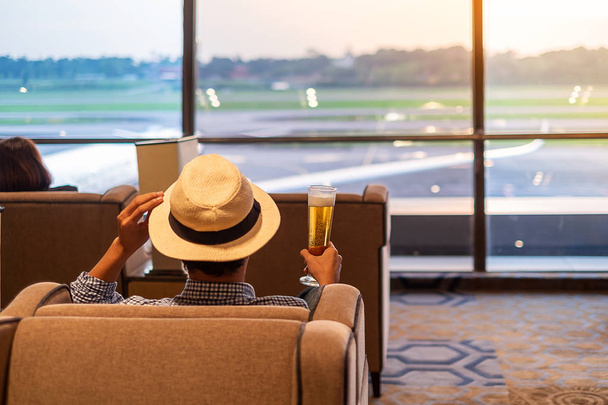 homem viajante com chapéu segurando copo de cerveja e olhando para avião
 - Foto, Imagem