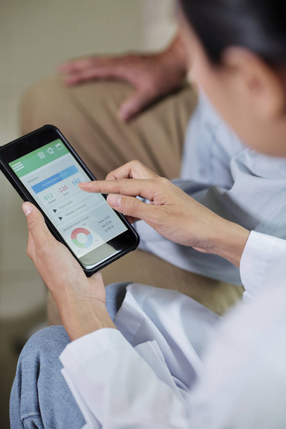 Close-up de médico fêmea segurando telefone celular e examinando os resultados de seu paciente em aplicação médica especial
 - Foto, Imagem
