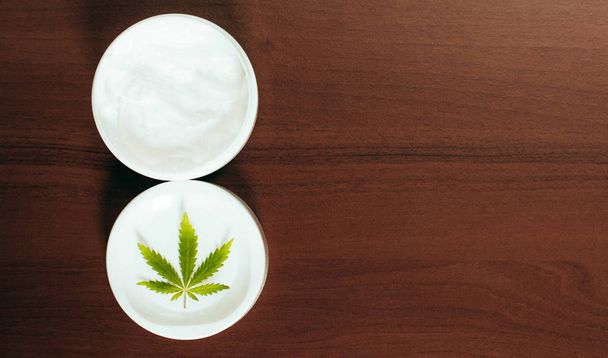 Moisturizing hemp hand cream in dose with green cannabis leaf. C - Photo, Image