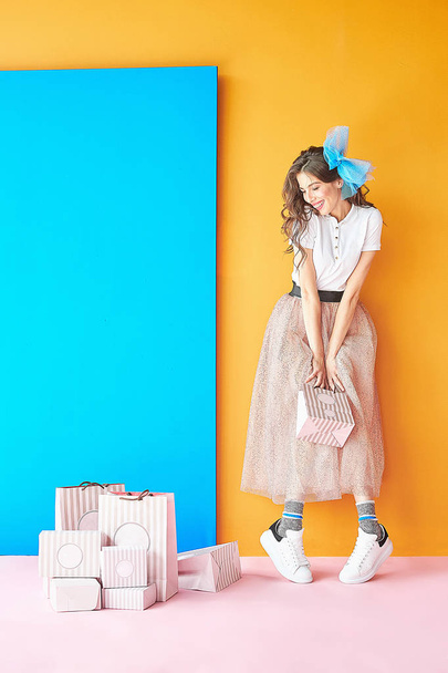Colorful portrait of happy confectioner woman in white shirt and pink glitter skirt. Candy colors. - 写真・画像