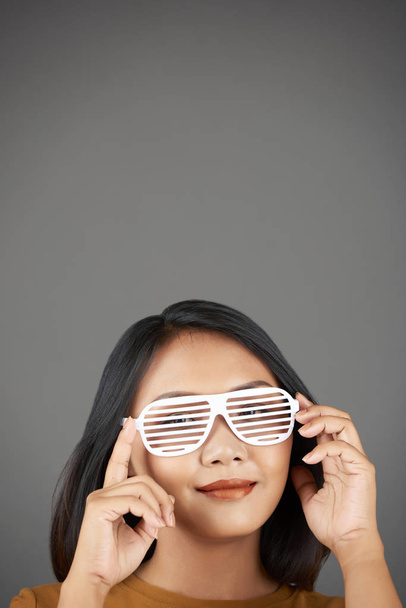 Lovely young smiling woman in shutter glasses posing against grey background - Photo, image