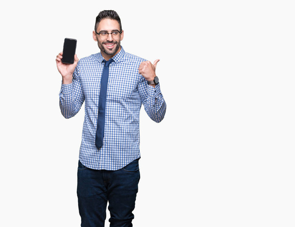 Fiatal üzleti ember találat smartphone képernyő felső elszigetelt háttér mutató és hüvelykujjával, akár a boldog arc mosolyogva oldalon mutatja - Fotó, kép