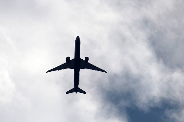 Lentokoneen siluetti taivaalla lähellä. Kaupallinen lentoonlähtö valkoisten pilvien taustalla
 - Valokuva, kuva
