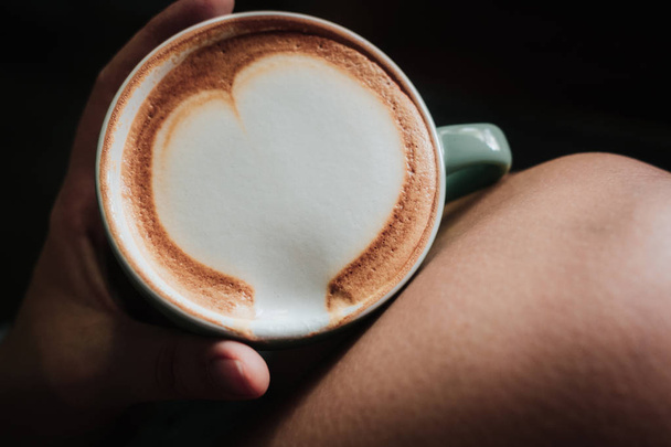 Donna mano che tiene il caffè con arte del latte del cuore
 - Foto, immagini