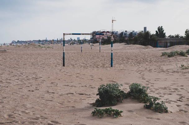 Απομόνωση τοπίο με Ποδόσφαιρο γκολ θέση στην παραλία άμμο με κανέναν. Πύλη ποδοσφαίρου στην παραλία στην ακτή της Μαύρης Θάλασσας στην Ουκρανία. Ελάχιστο τοπίο ακτογραμμής με ανομοιόμορφη αμμώδη επιφάνεια. Θέα στη θάλασσα  - Φωτογραφία, εικόνα